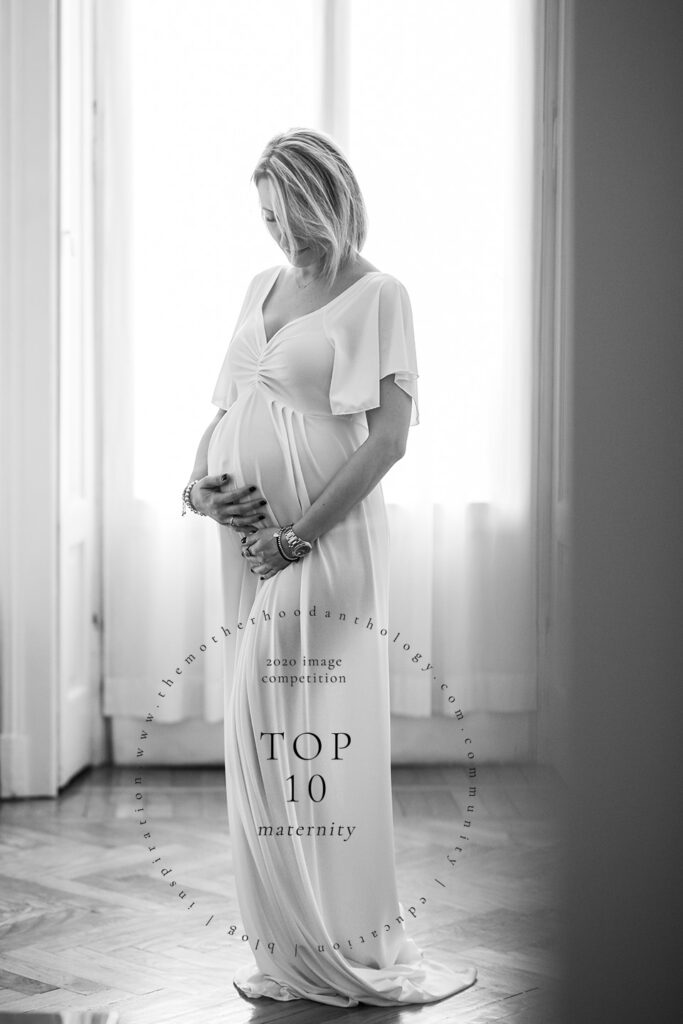 Elegant pregnancy photography of a woman holding her belly standing in her Italian apartment
