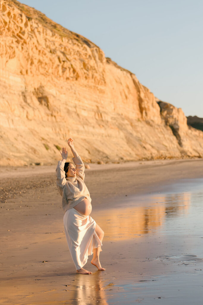 Expecting mother standing beside the ocean enjoying the sunset