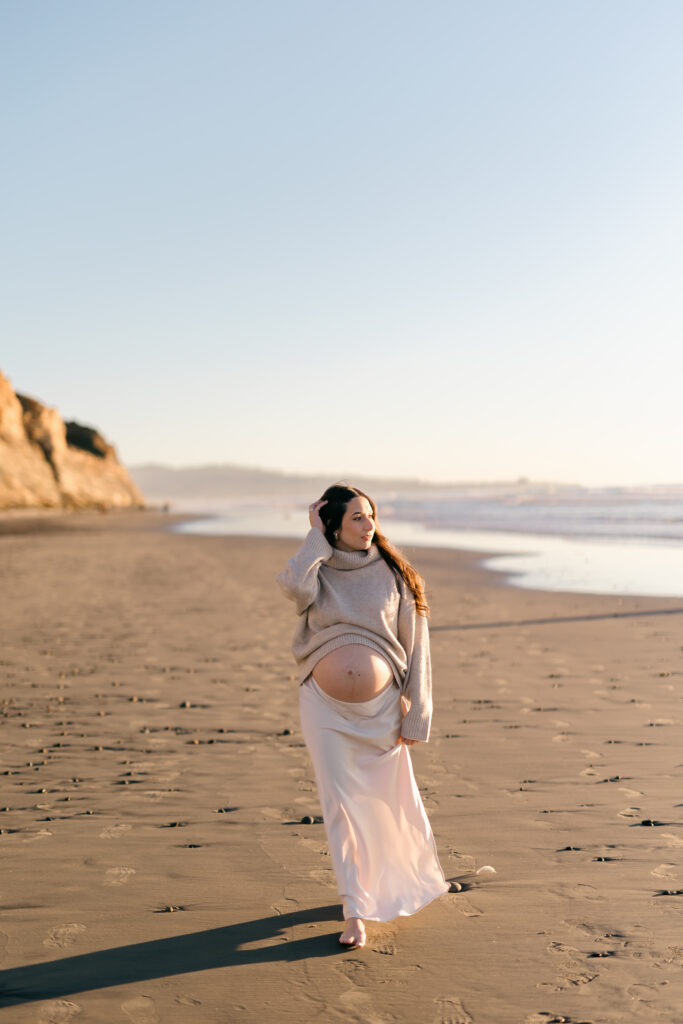Expectant mother walking beside the ocean on a San Diego beach