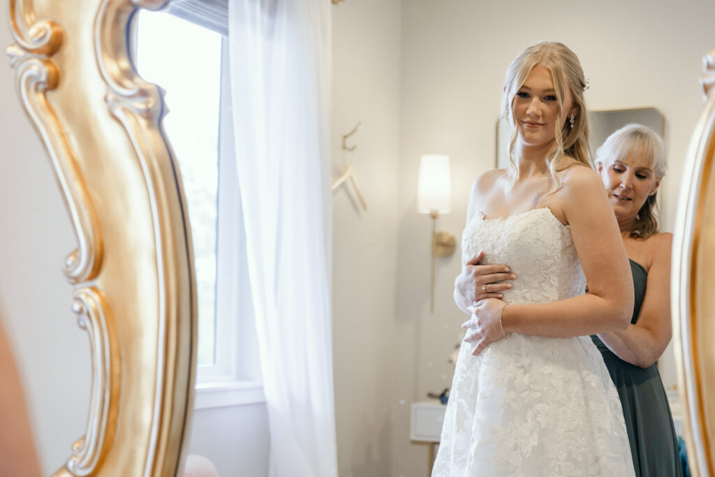 Mother of the bride helping to button up the wedding dress