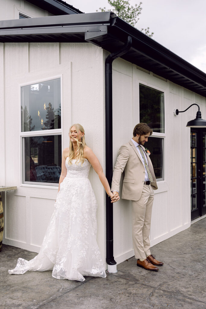 First emotional touch of bride and groom at the corner of the White Barn at The View at Madge Gulch