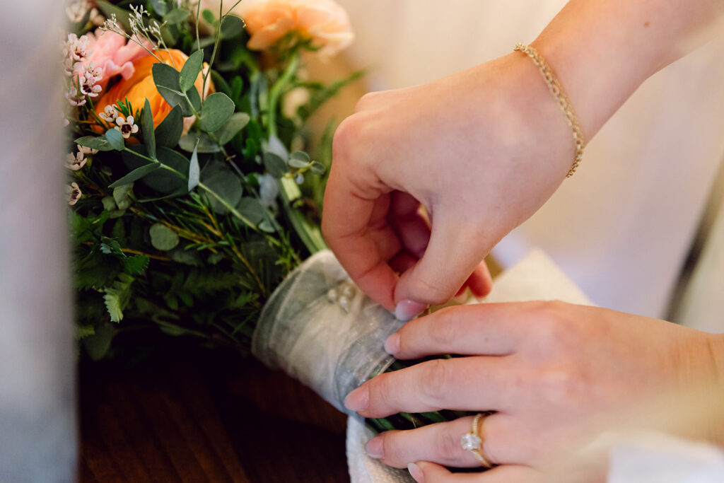 Bride putting a little medal to her flowers