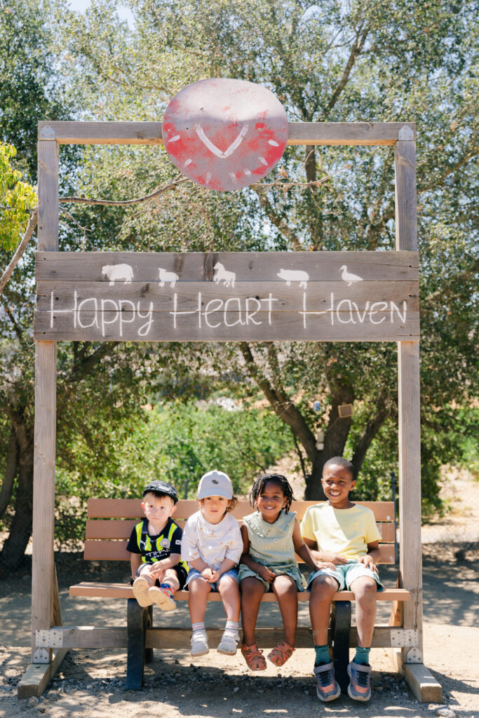 Children posing under the sign of Happy Heart Haven Farm