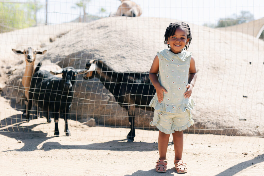 Birthday girl posing with goats at the farm