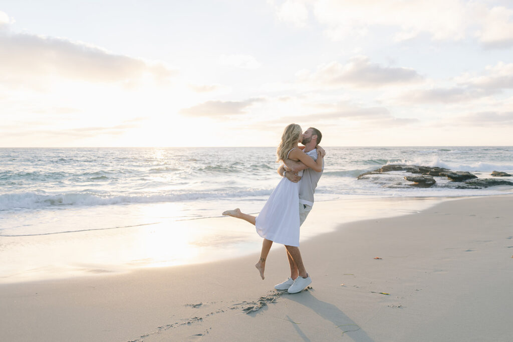 Couple kissing beside the ocean during sunset at Windeand Sea beach La Jolla