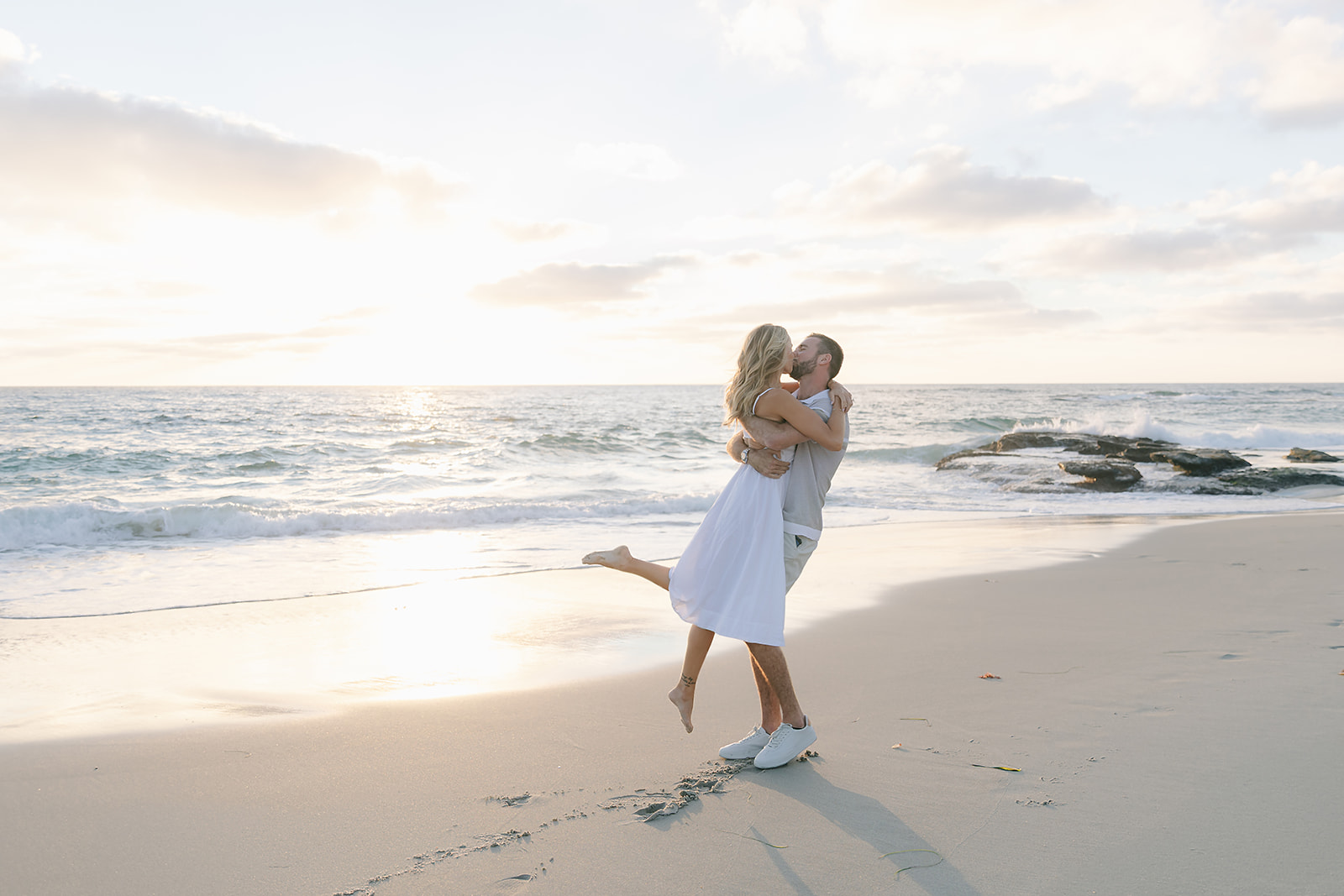 Couple kissing beside the ocean during sunset at Windeand Sea beach La Jolla